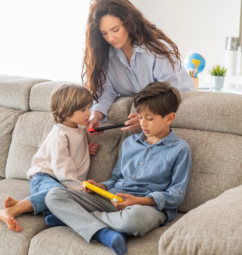 moeder met gameconsole in had en twee kinderen die gamen