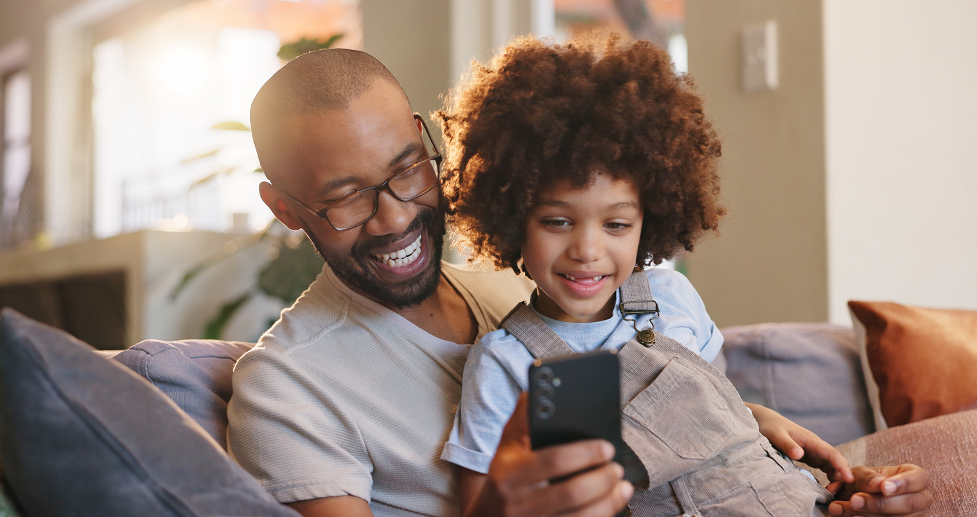 blije man en kind met telefoon op de bank