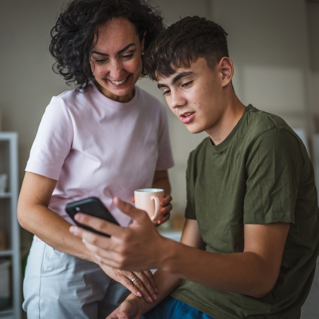 Volwassen vrouw en tiener kijken samen naar een smartphone.
