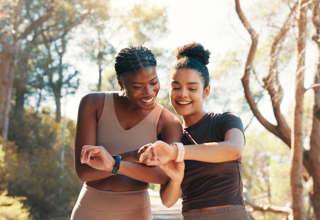 twee sportieve vrouwen die buiten op hun smartwatch kijken