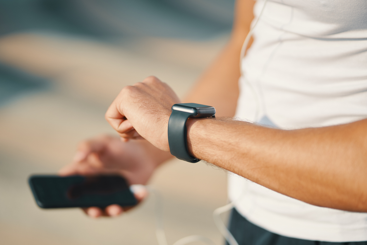 persoon die naar smartwatch kijkt en mobiel in de hand heeft